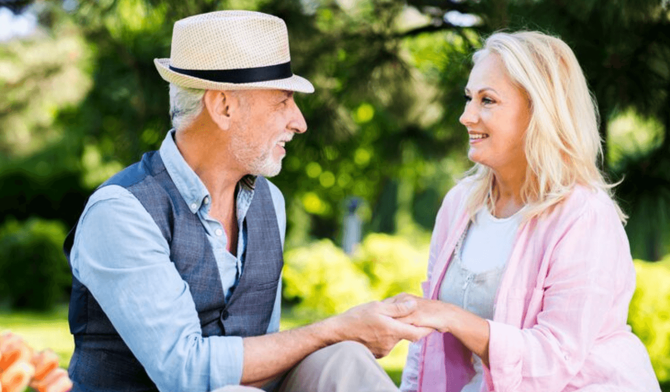 Mature couple outdoors in a garden-like public setting